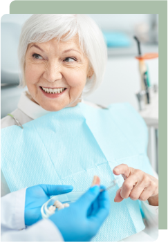 An elderly woman smiling at the dentist during a consultation, showing trust and satisfaction with her dental care experience.