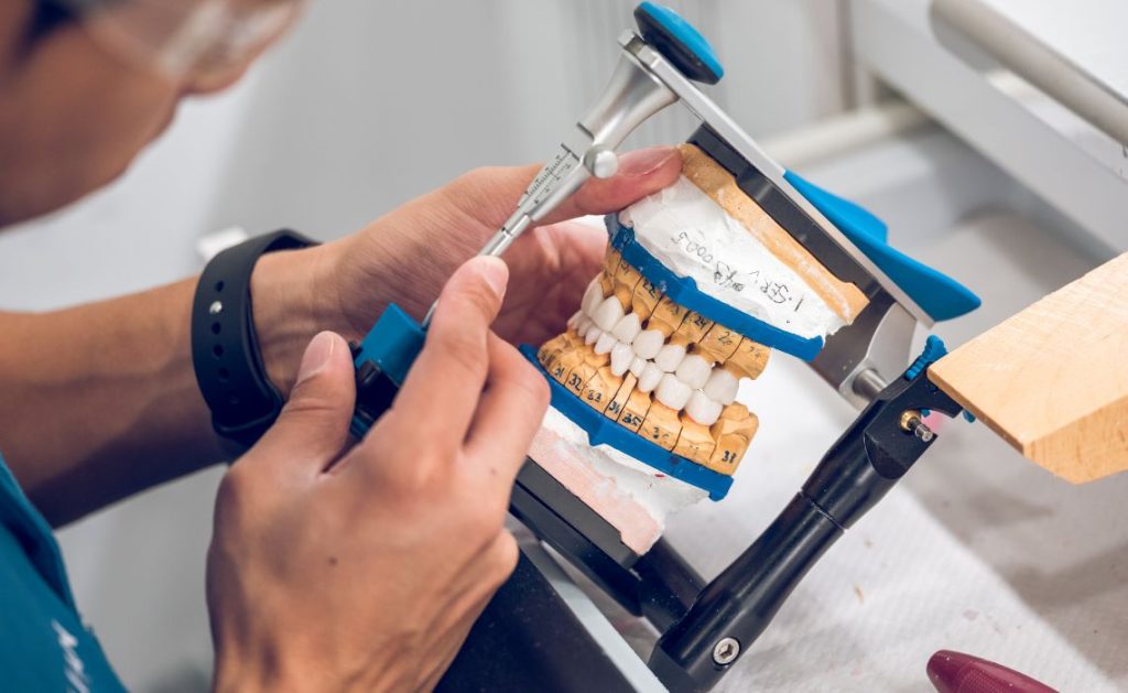 A dental technician meticulously works on creating a set of custom dentures, using precision tools to ensure perfect fit and functionality.