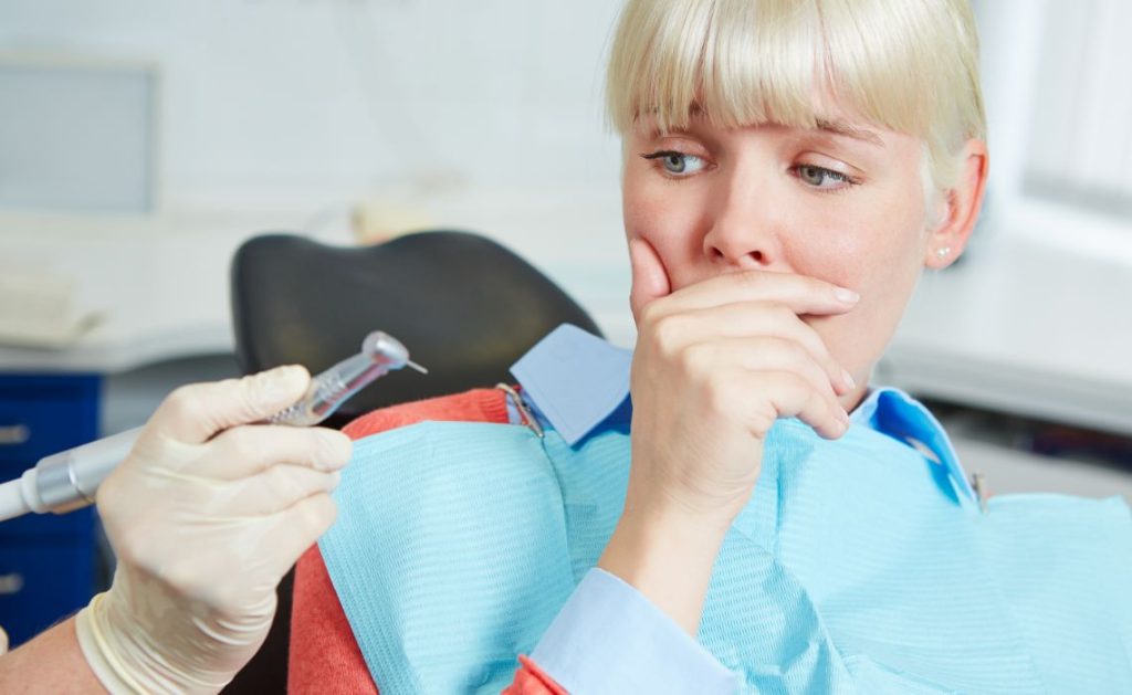 A patient looks anxious while the denturist prepares tools, illustrating common dental anxiety during routine appointments.